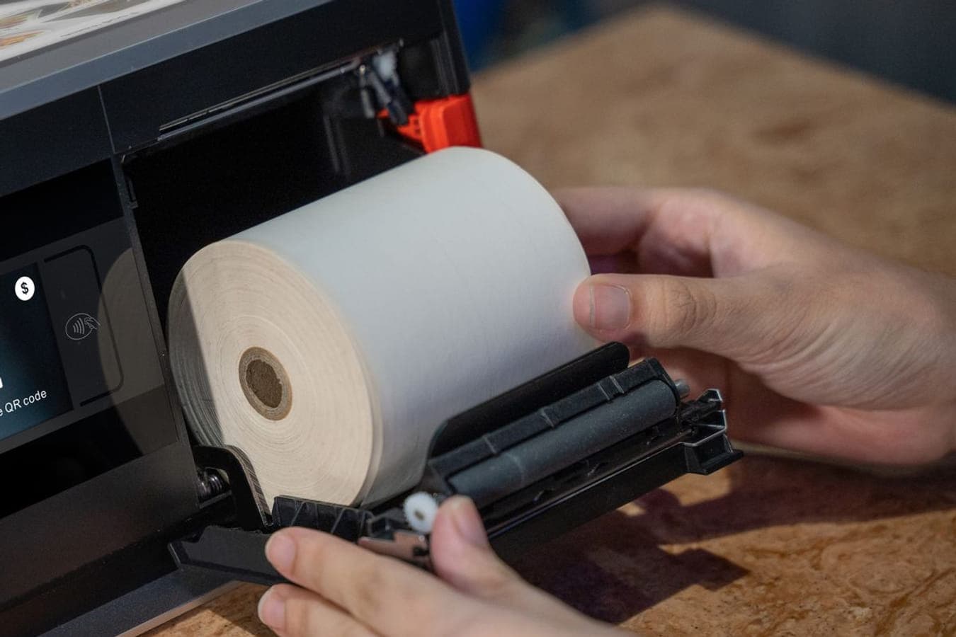 An 80mm paper roll being loaded into a till’s built-in printer