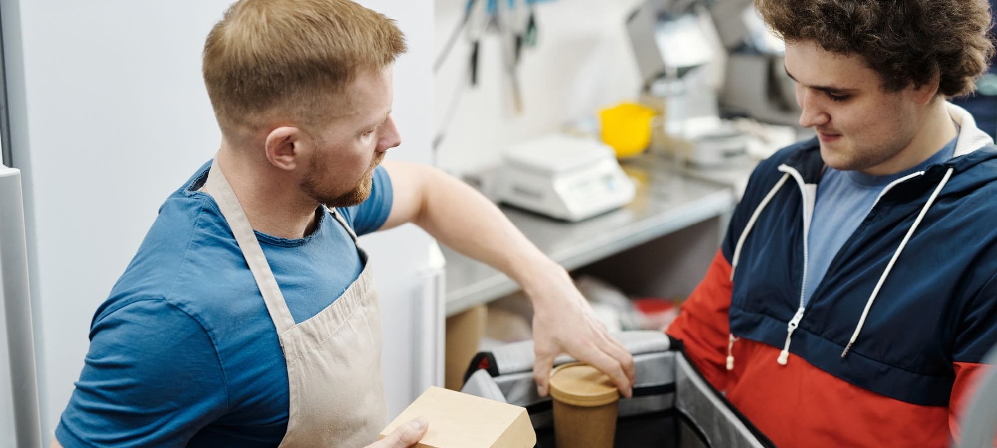 Kitchen staff boxing a finished order and handing it over